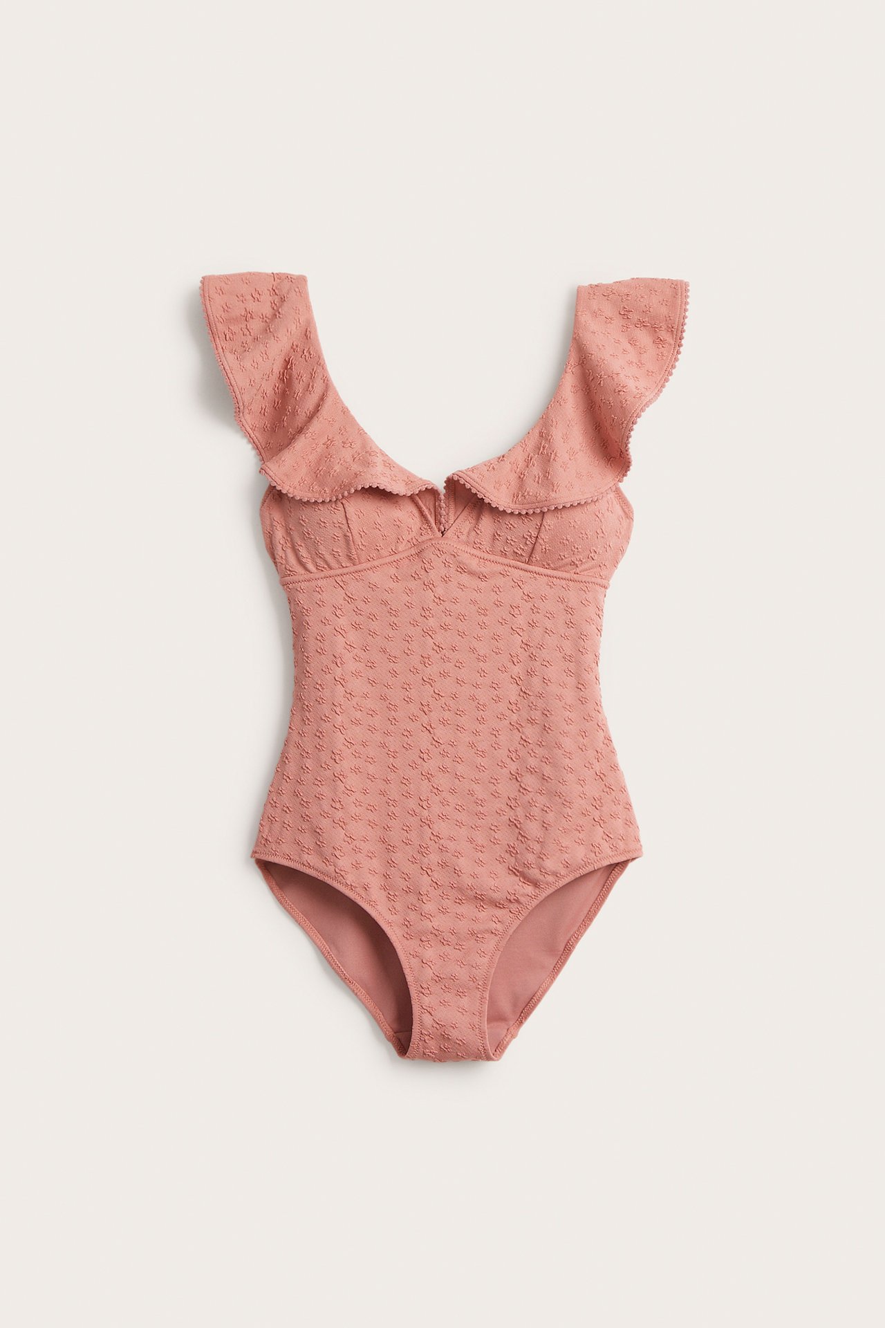 Vorderansicht eines rosa Damen-Badeanzugs mit Jacquard-Blumen, großen Rüschen und Pompon-Besatz.
