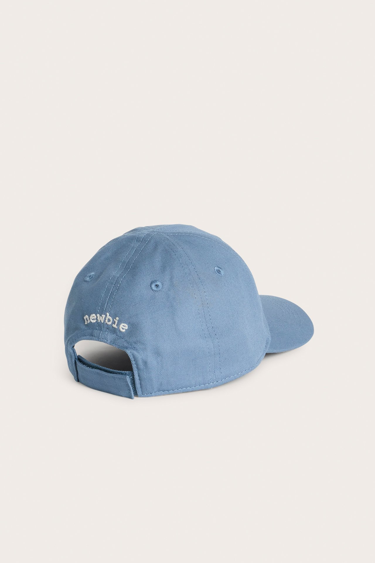 Rückansicht einer blauen Baumwollkappe mit weißer 'newbie'-Stickerei auf der Rückseite.