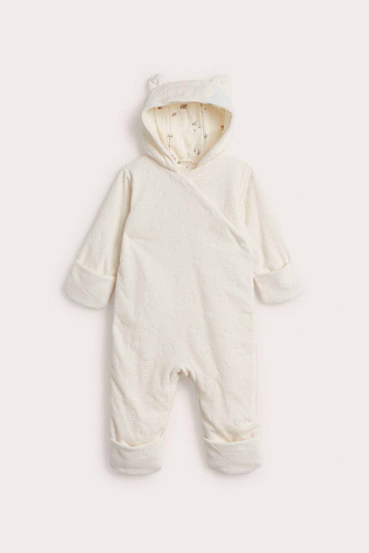 Front view of an offwhite velour baby coverall with embossed pattern, ear hood, and printed lining.