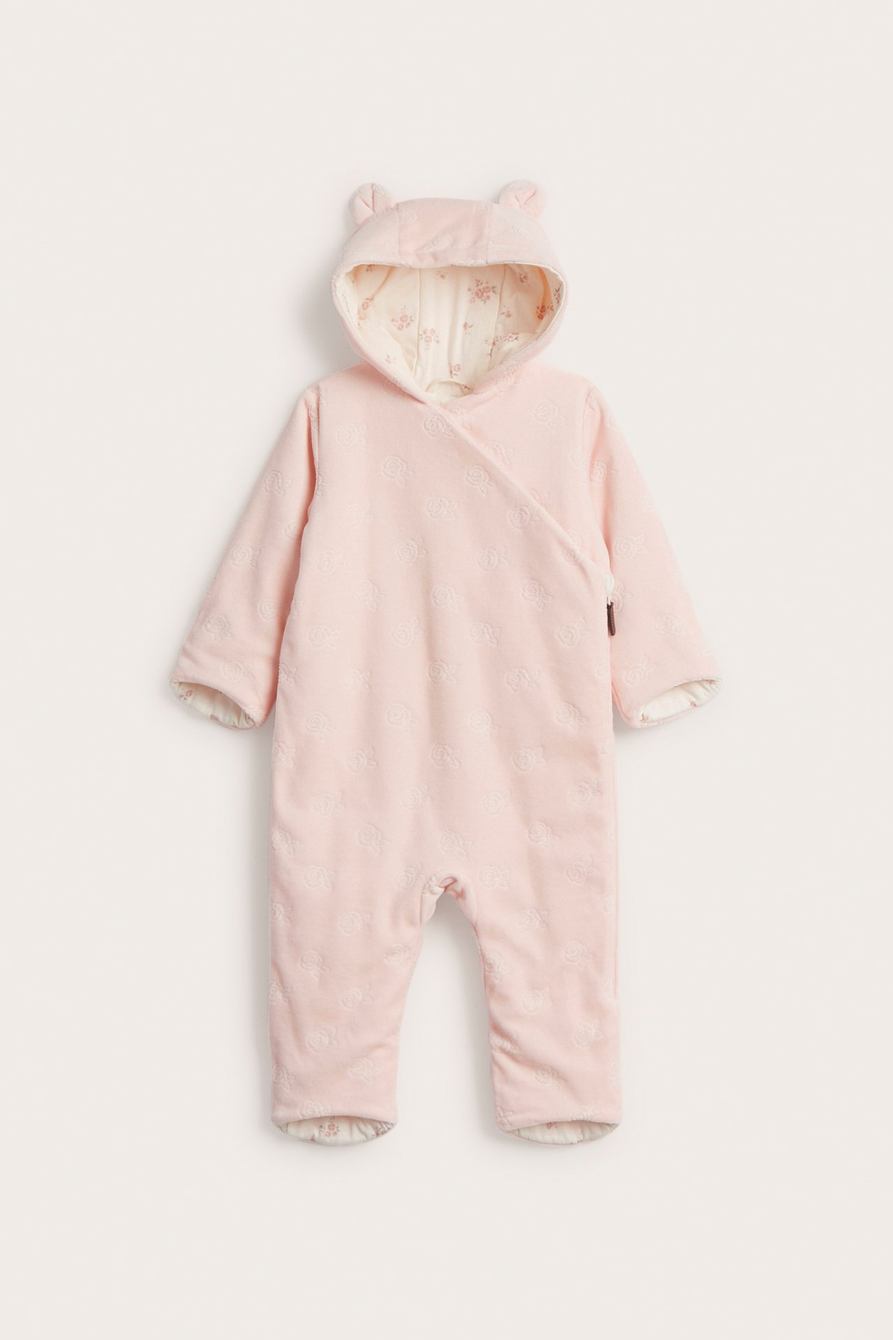 Vorderansicht: Babyrosa Velours-Overall mit Prägemuster, Ohrenkapuze, diagonalem Reißverschluss und Blumenfutter.