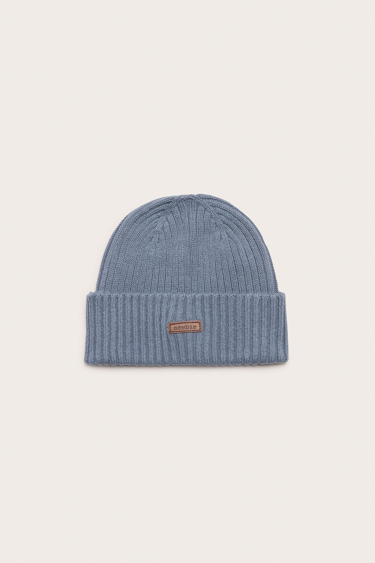 Front view of a blue rib-knitted baby/kid's beanie with a fold-up brim and a small label.