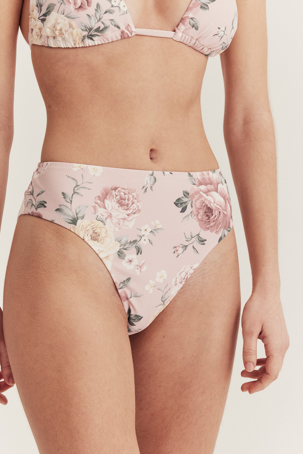 Front view of a woman wearing a pink floral high-waisted bikini bottom and a matching bikini top.