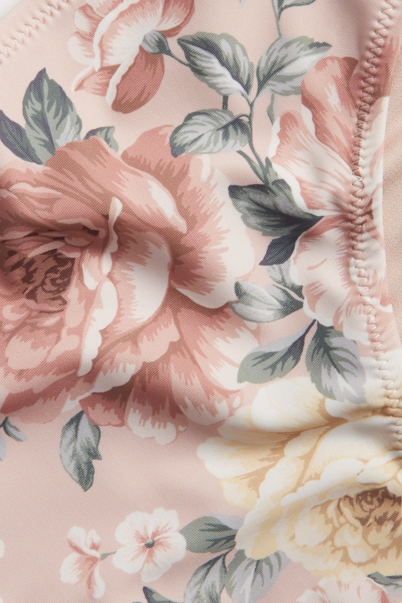 Close-up of a pink floral bikini bottom with a pattern of pink and yellow roses.