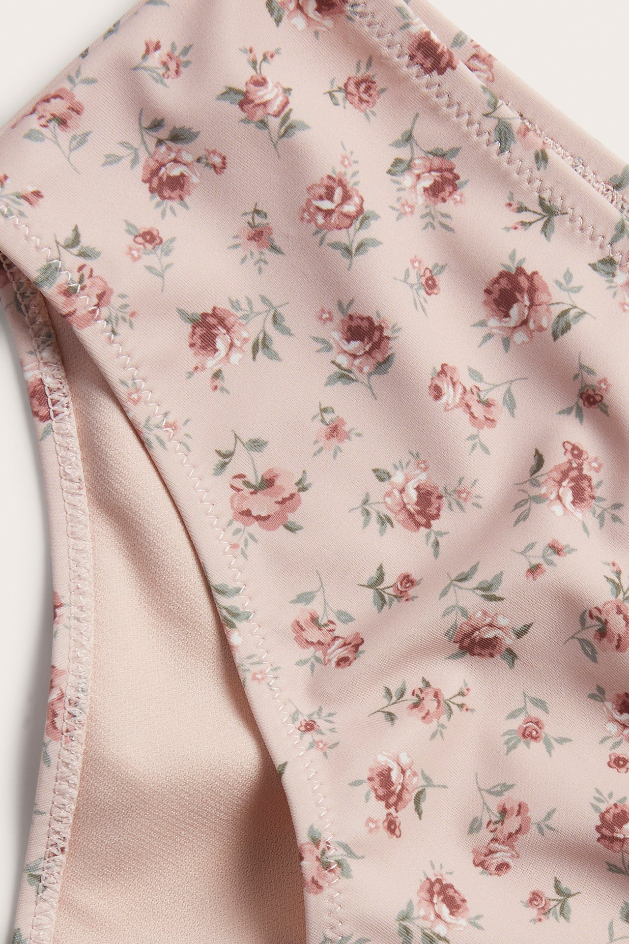Nahaufnahme einer rosa geblümten High-Waist-Bikinihose, die Stoff und Futter zeigt.