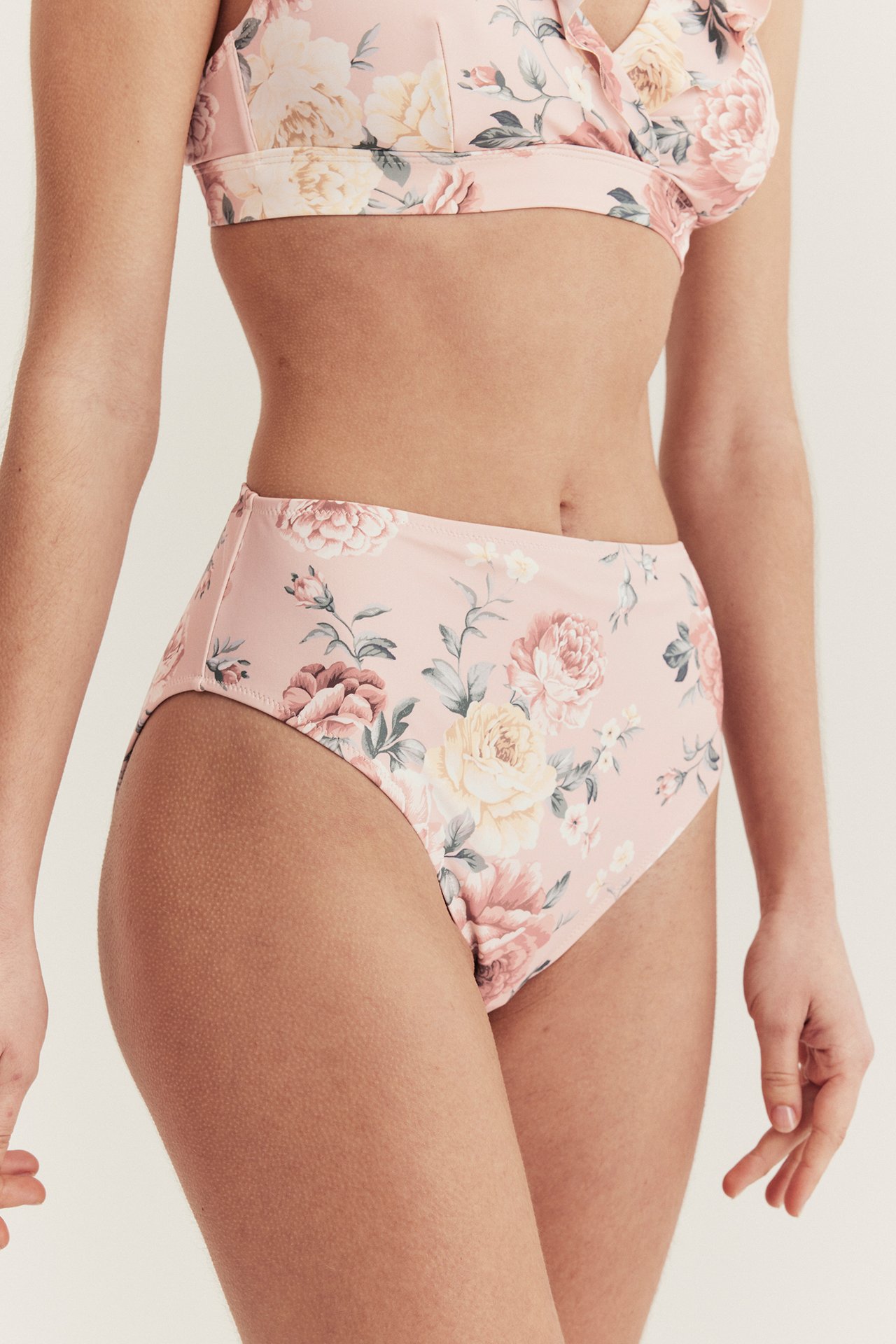 Front view of a woman wearing a pink high-waisted floral bikini bottom and a matching bikini top.
