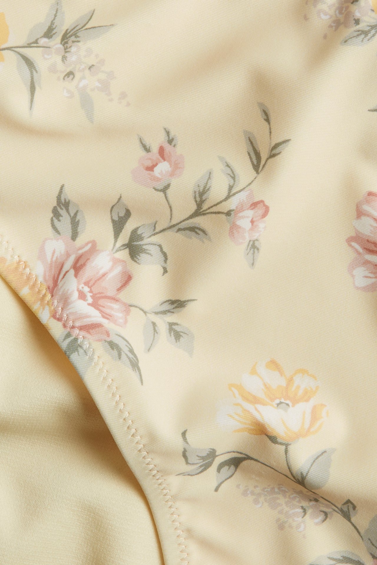 Close-up of a light yellow high-waisted bikini bottom with a pink and yellow floral pattern.