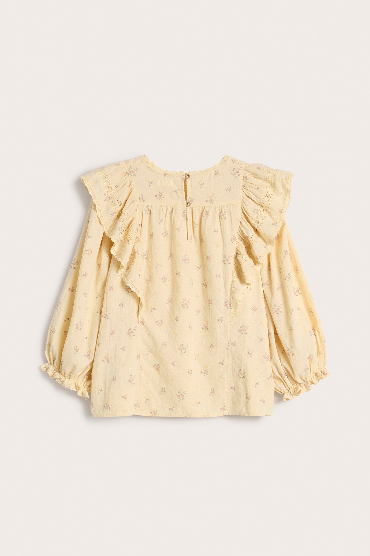 Front view of a yellow floral cotton blouse with lace-decorated ruffles, 3/4 puff sleeves, and a back button.