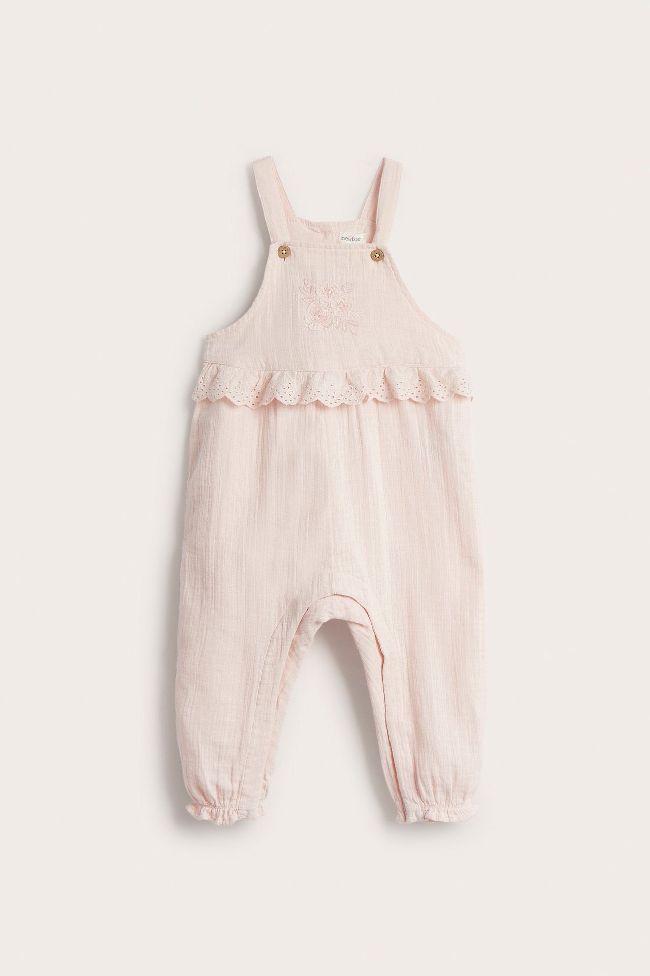 Vorderansicht: hellrosa Baby-Baumwoll-Latzhose mit Bruststickerei, Spitzenrüsche und verstellbaren Trägern.
