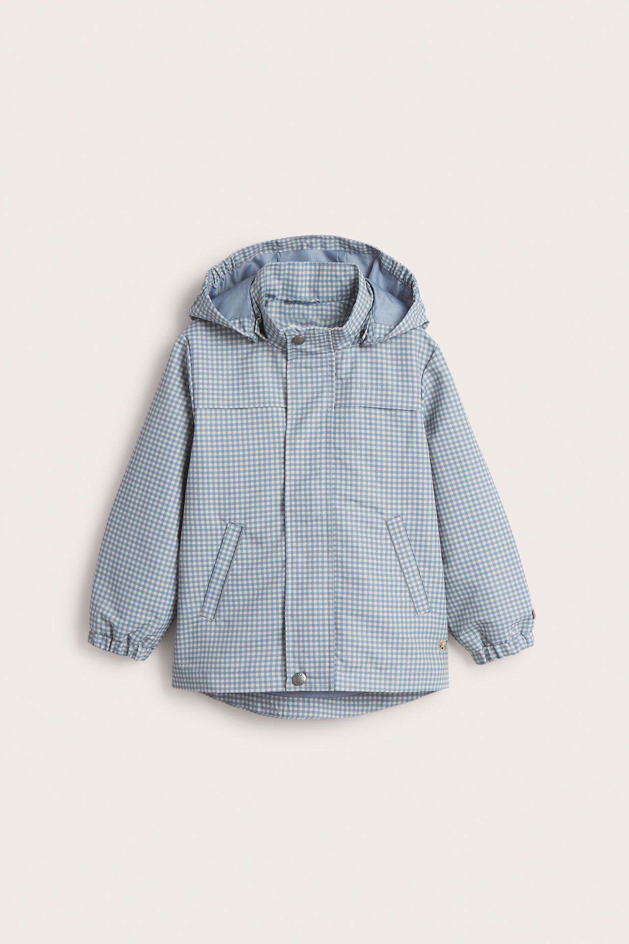 Vorderansicht: Hellblaue karierte wasserabweisende Kinderjacke mit Kapuze, Reißverschluss und zwei schrägen Taschen.