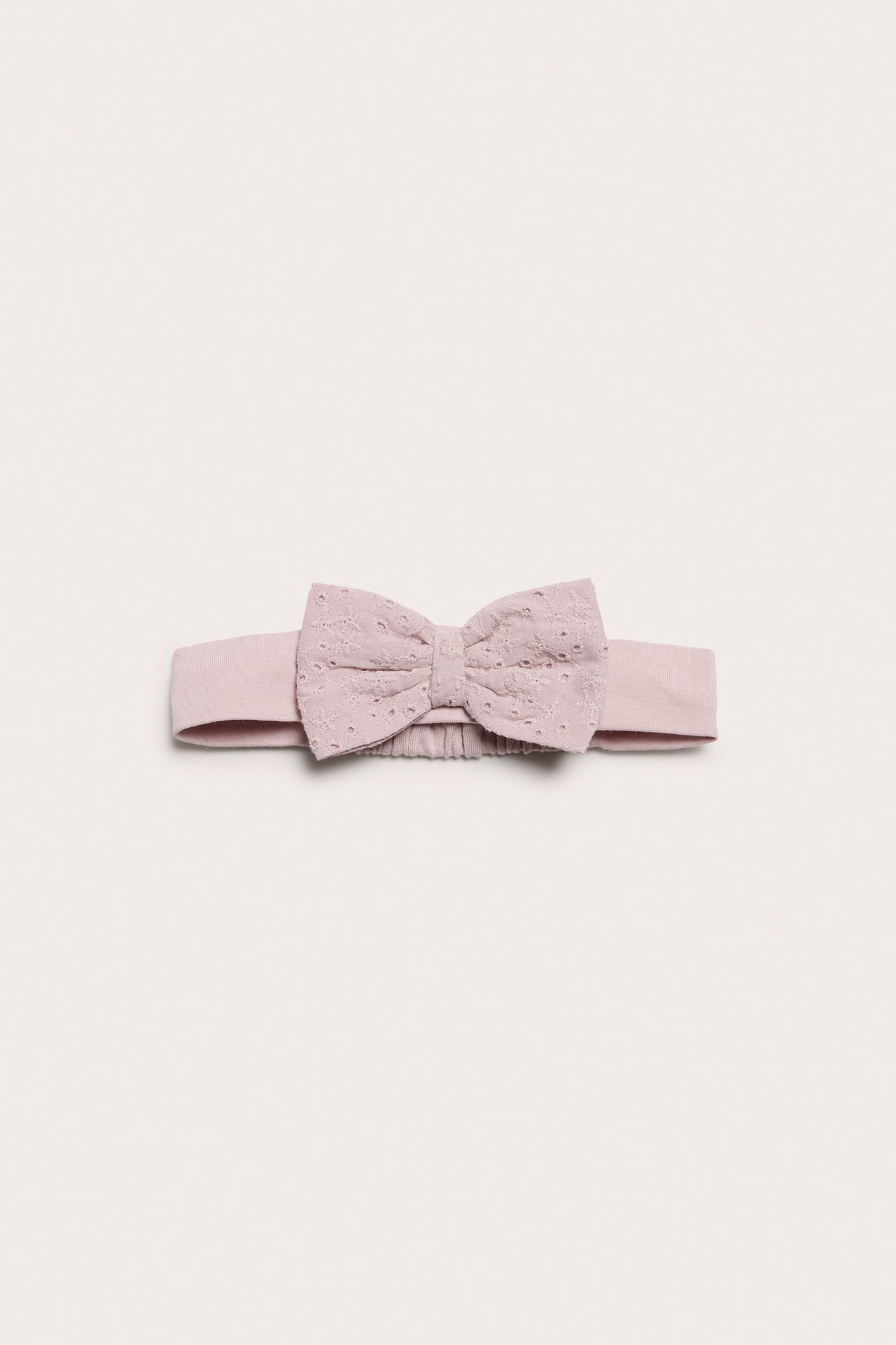Front view of a pink jersey baby headband with a delicate lace bow and elastic back.