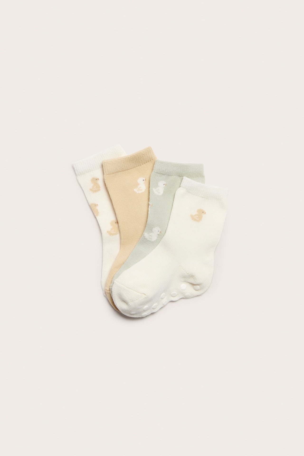 Draufsicht auf vier pastellfarbene Babysocken: cremefarben, beige, hellgrün, mit Entenmustern und Anti-Rutsch-Sohlen.