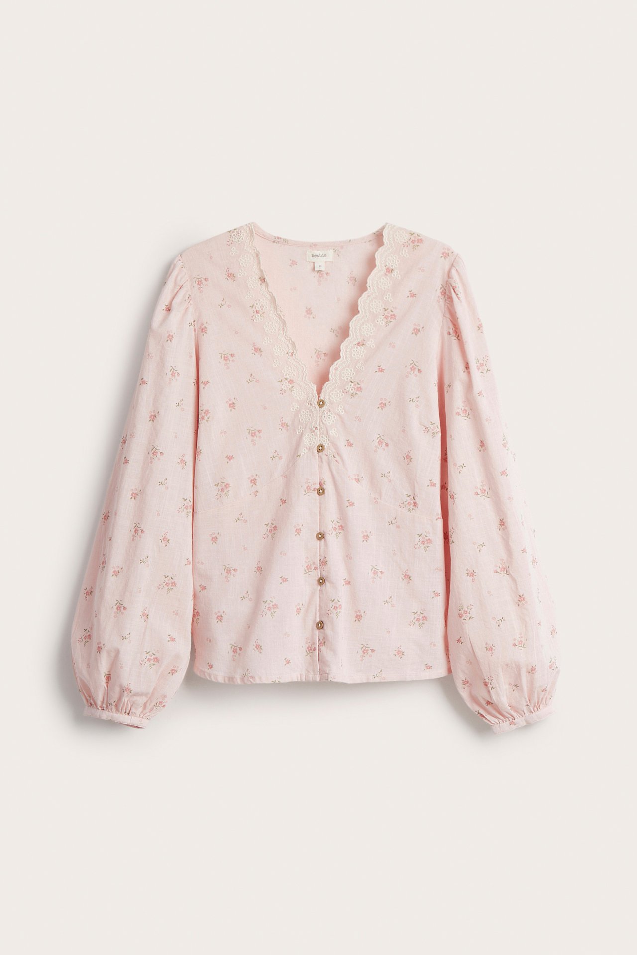 Vorderansicht: Hellrosa geblümte Baumwollbluse mit Spitzen-V-Ausschnitt, Puffärmeln und bezogenen Knöpfen.