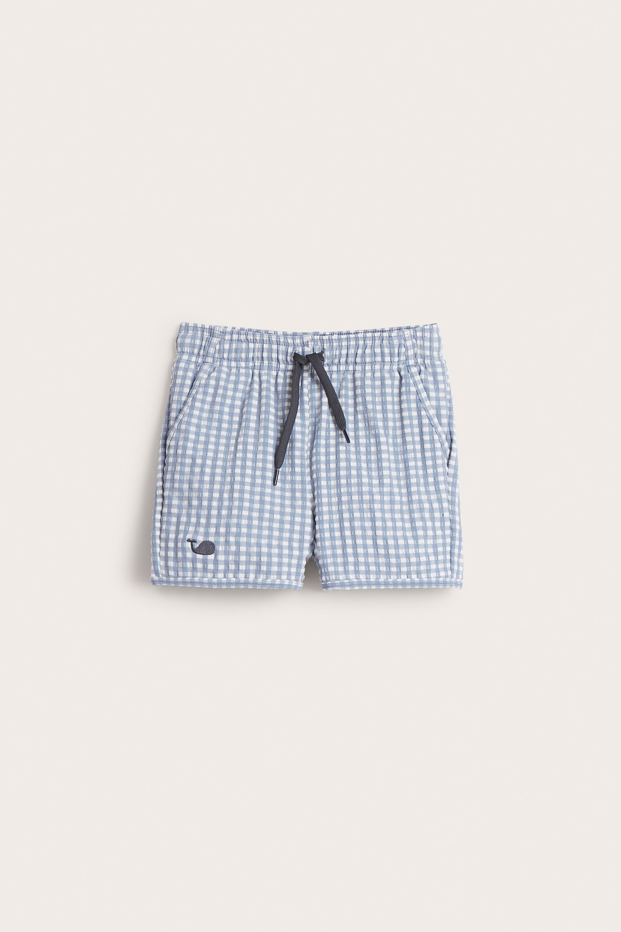 Vorderansicht von karierten Kinder-Badeshorts aus blau-weißem Seersucker mit Gummizug, dunklem Kordelzug und Walstickerei.