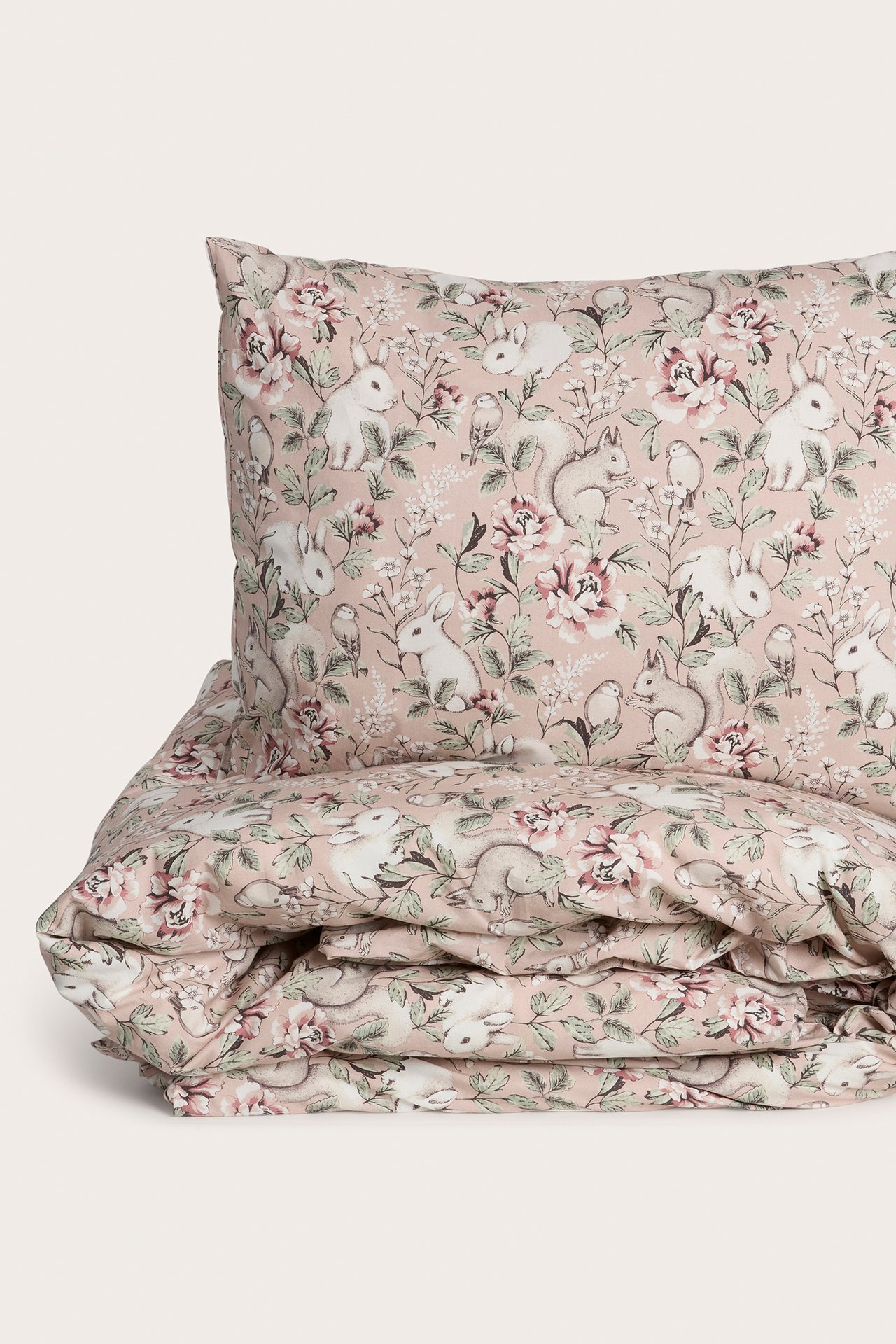Nahaufnahme eines rosa Baumwoll-Bettwäschesets mit Blumen- und Tiermuster.
