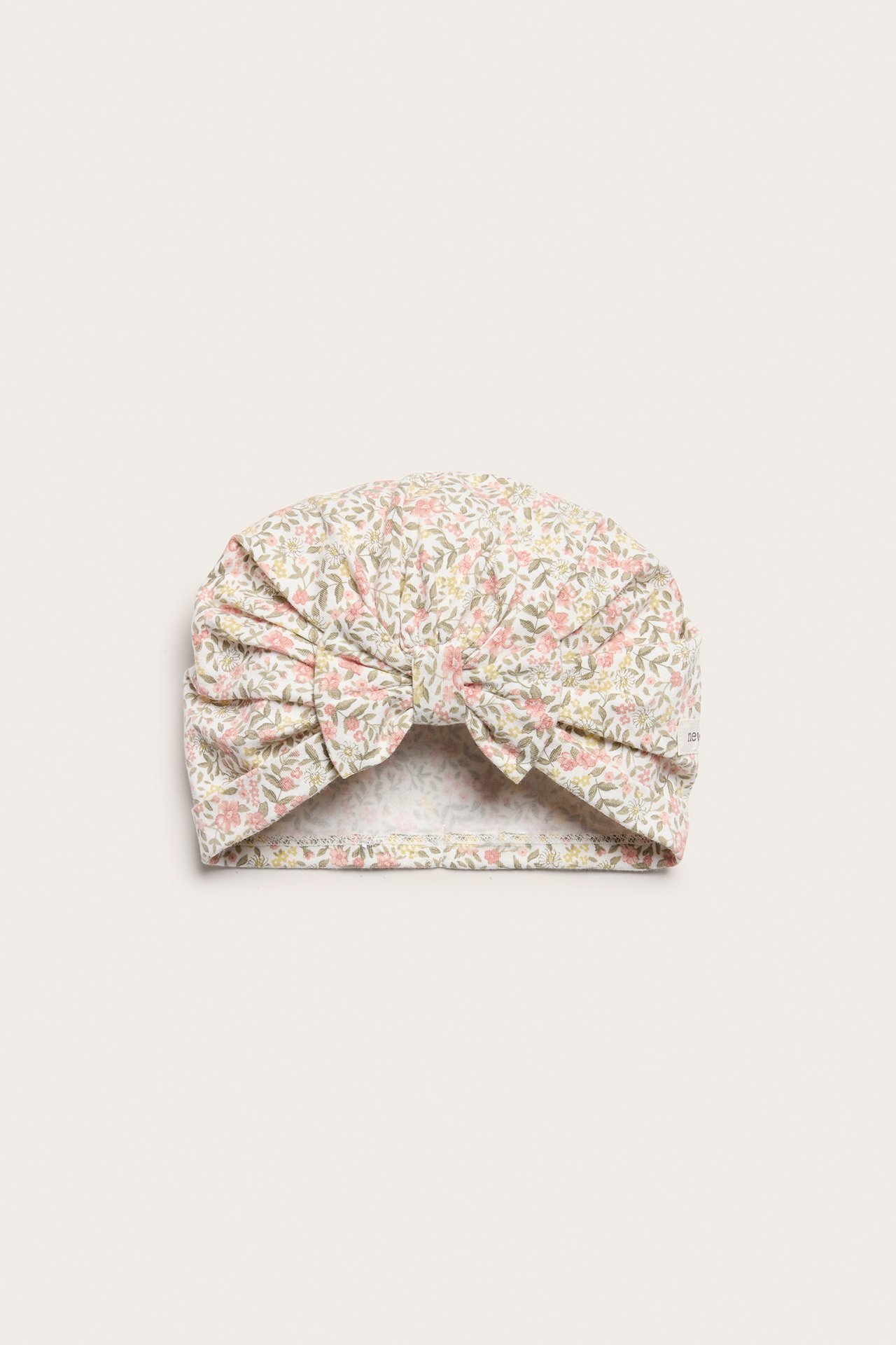 Vorderansicht: Off-white geblümte Jersey-Turbanmütze für Baby/Kind mit großer Schleife.