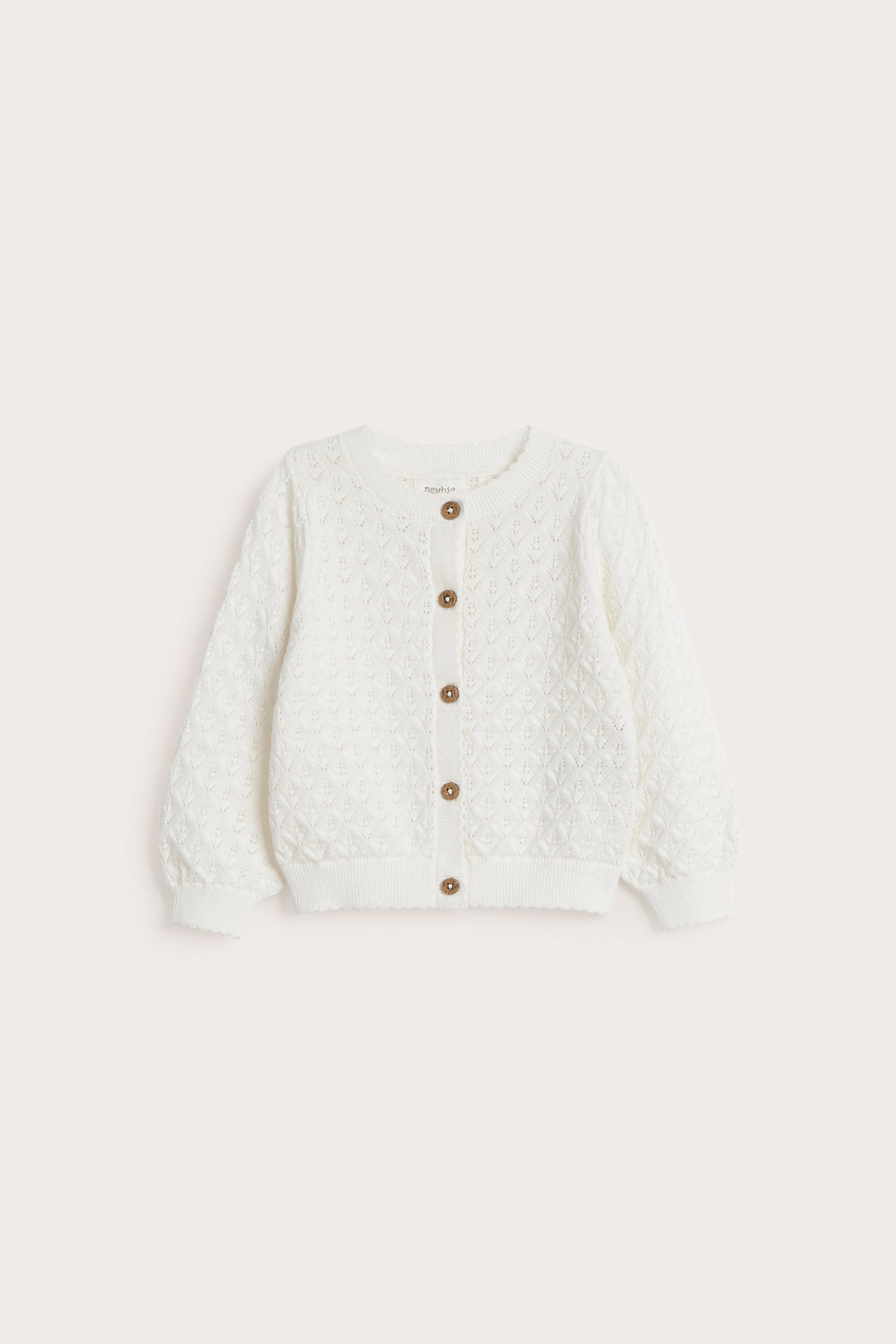 Vorderansicht einer cremefarbenen gemusterten Baby-Strickjacke mit braunen Knöpfen und Wellenkanten.