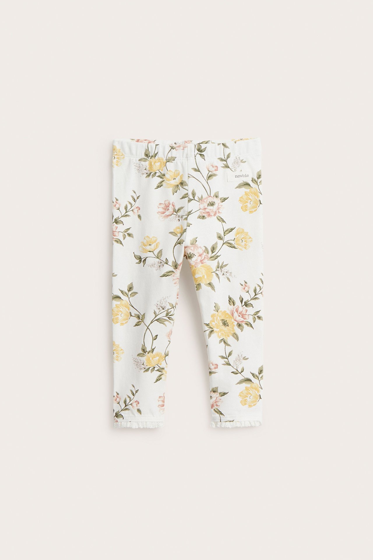 Front view of offwhite baby leggings with yellow and pink floral print, elastic waist, and lace cuffs.