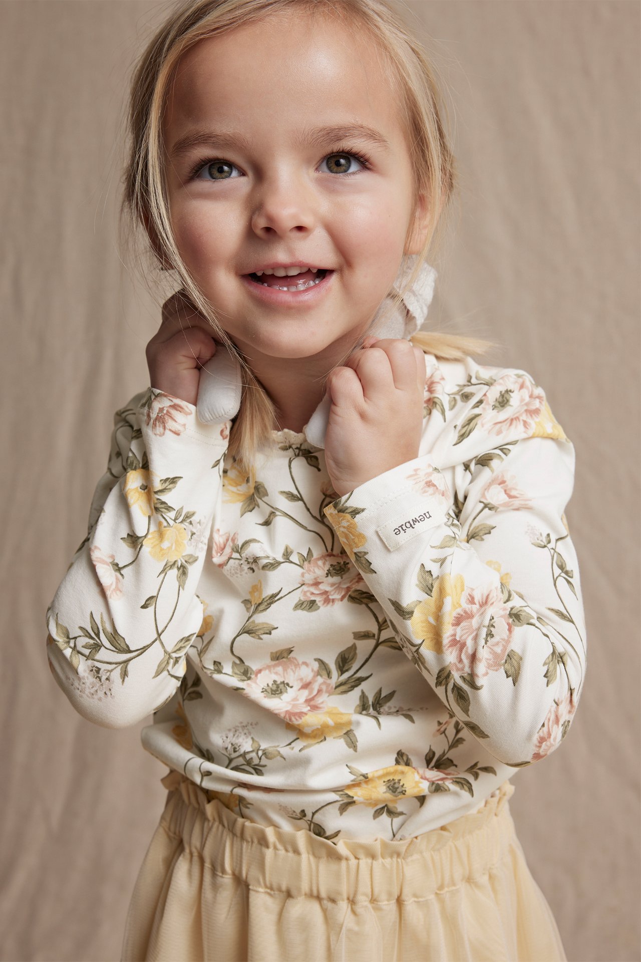 Front view: Kid in off-white floral jersey top with lace trim and light yellow tulle skirt.