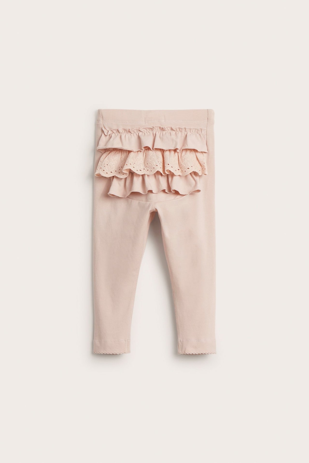 Hellrosa Baby-Baumwoll-Leggings mit Rüschen, Spitze am Rücken und Wellensaum, Vorderansicht.