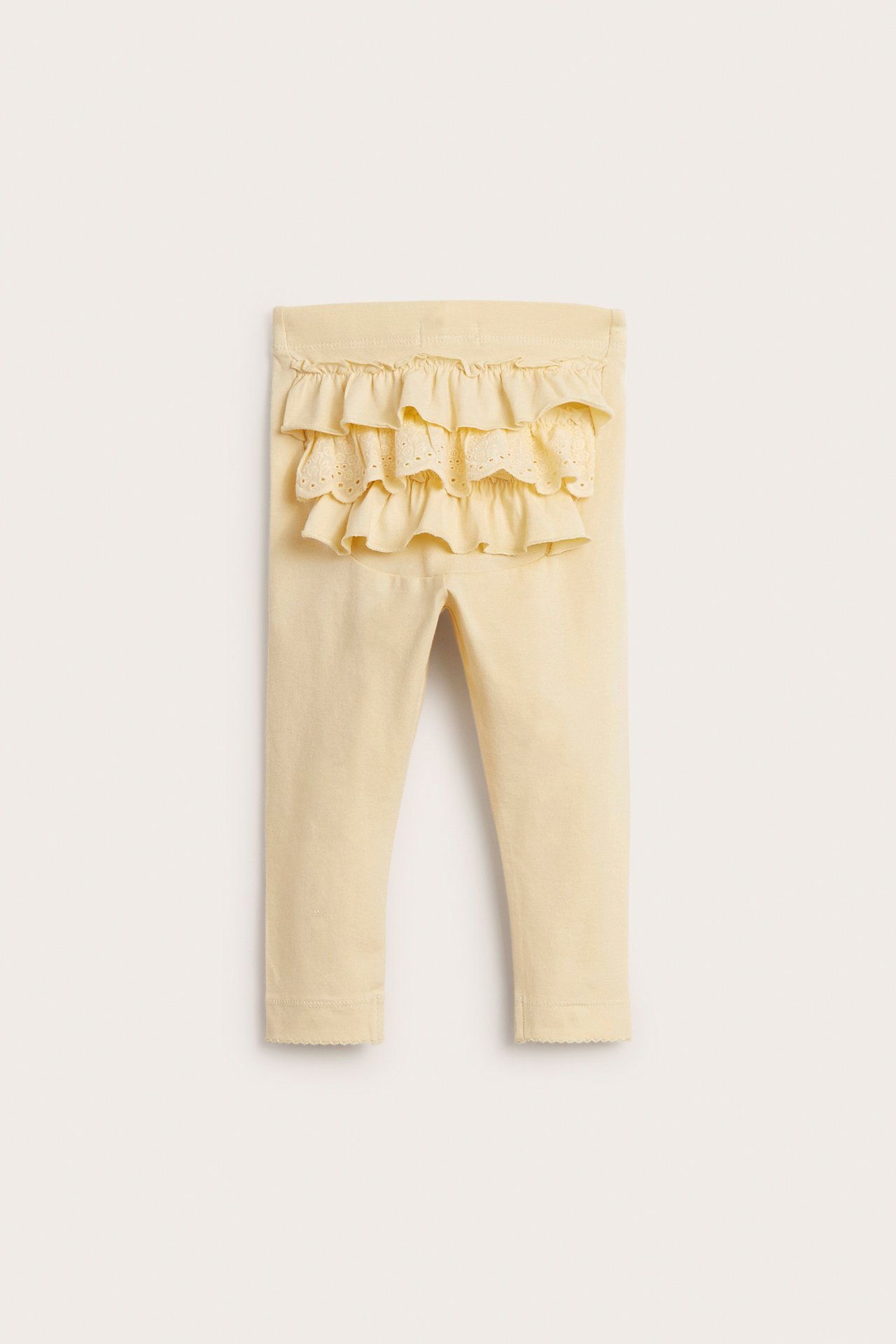 Rückansicht: gelbe Baby-Baumwollleggings mit Gummibund, Rüschen und Spitzendetails.