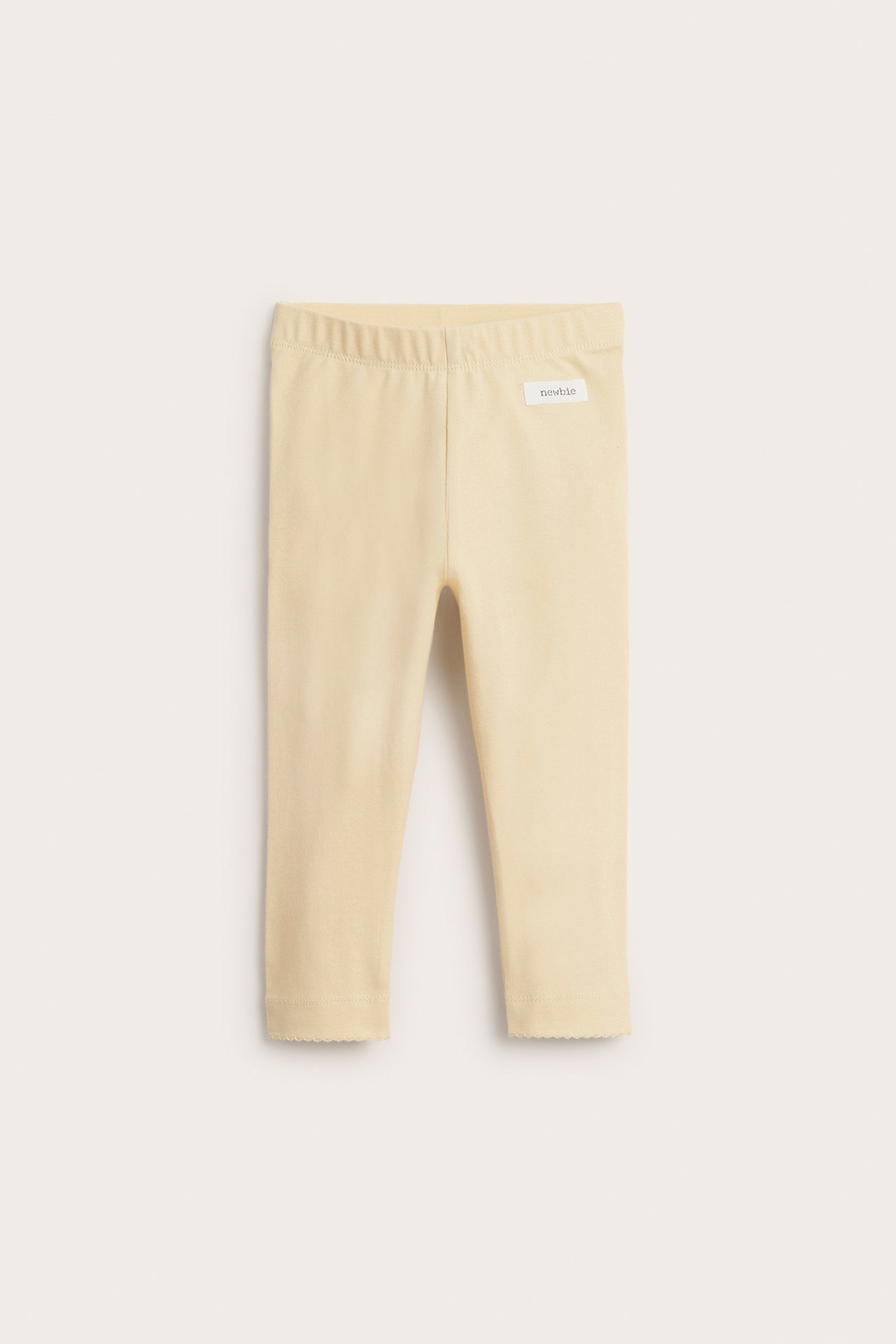Vorderansicht von hellgelben Baby-Leggings mit Gummibund und gewelltem Saum.