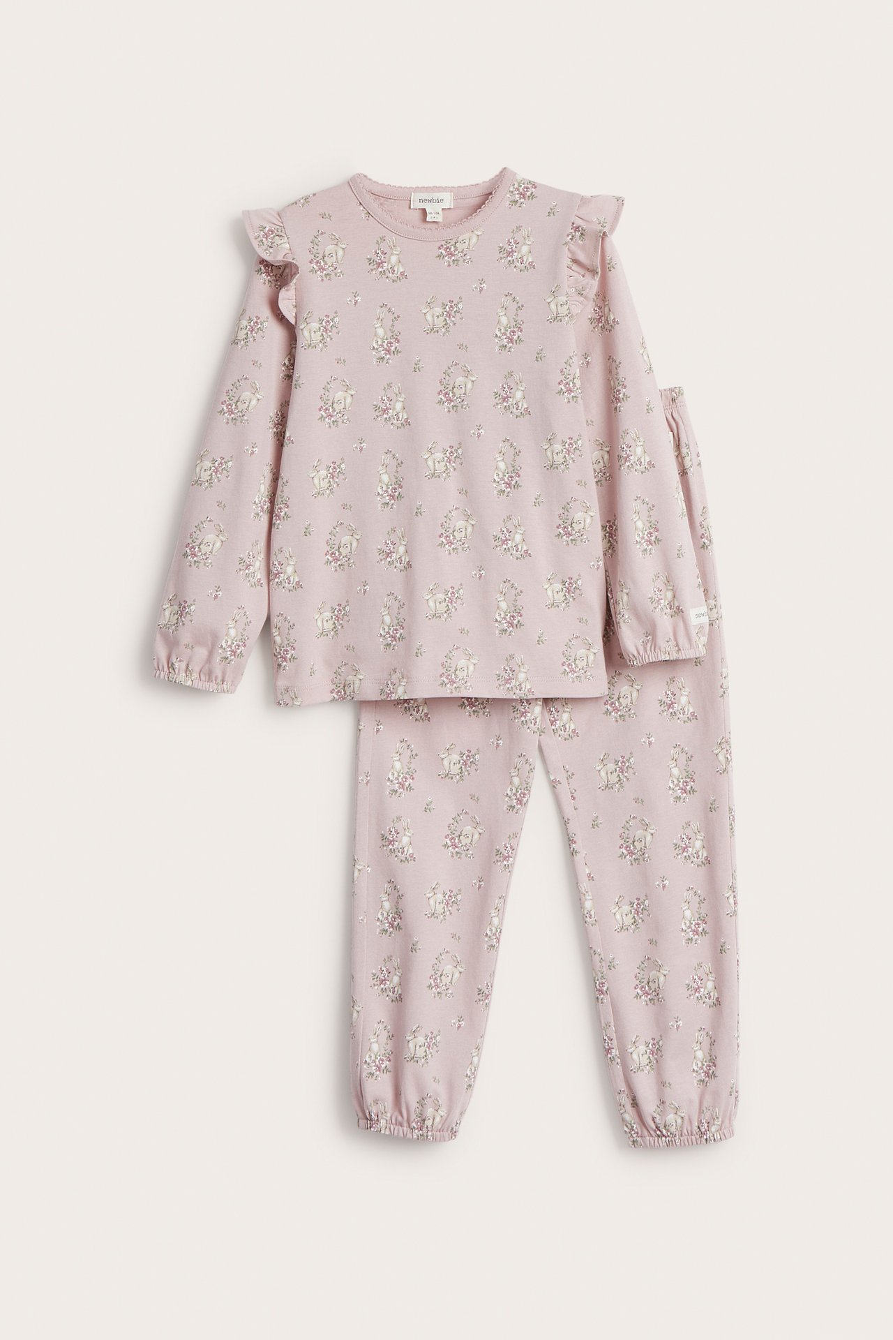 Front view of a kid's pink cotton pyjama set with shoulder ruffles and a floral rabbit print.