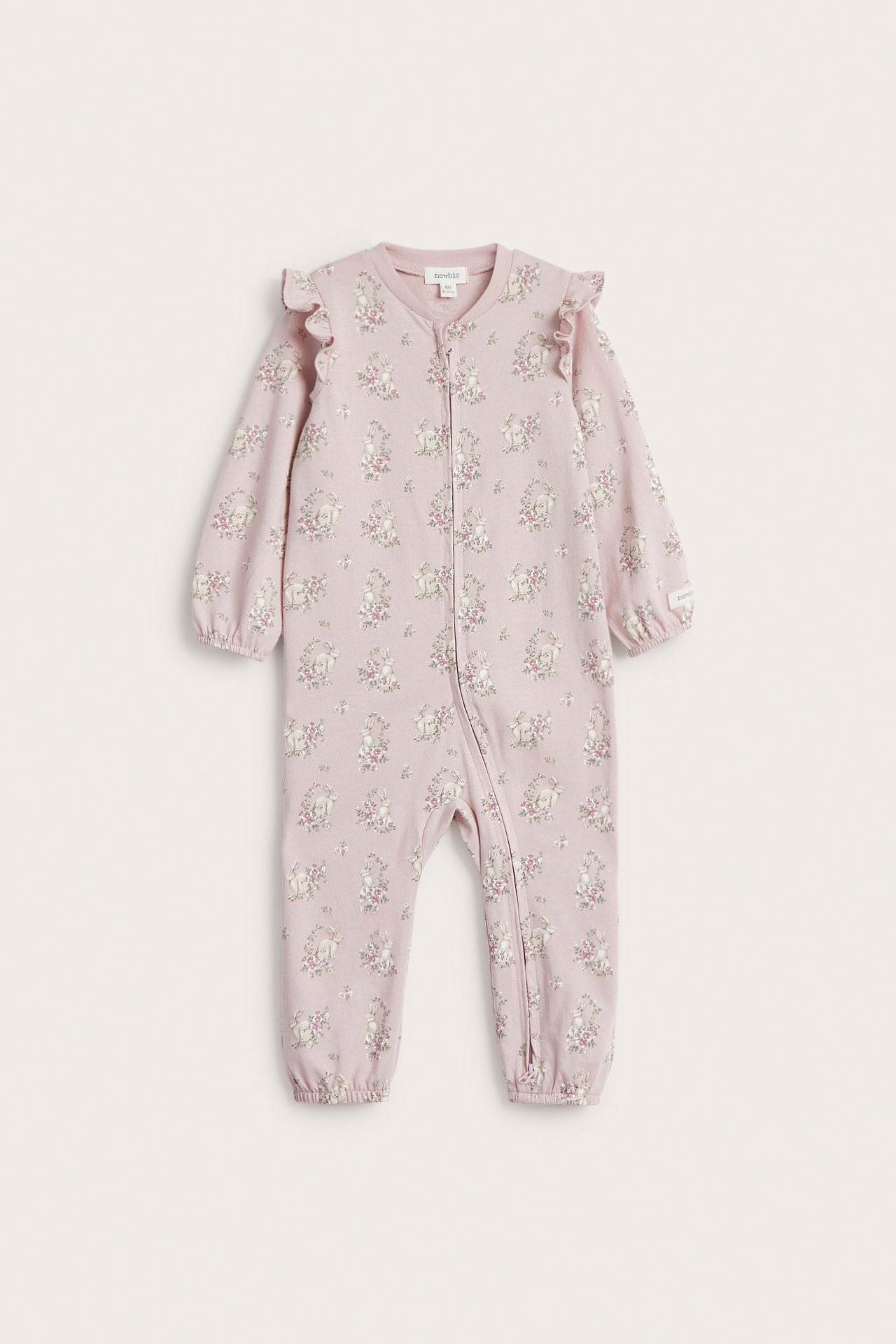 Front view: Pink cotton baby pyjamas with floral rabbit print, shoulder ruffles, and two-way zipper.