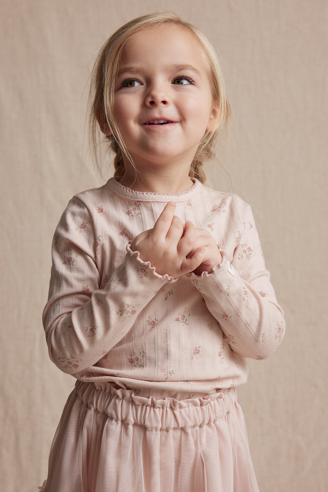 Front view: Kid in light pink floral pointelle rib long-sleeved top and matching pink tulle skirt.
