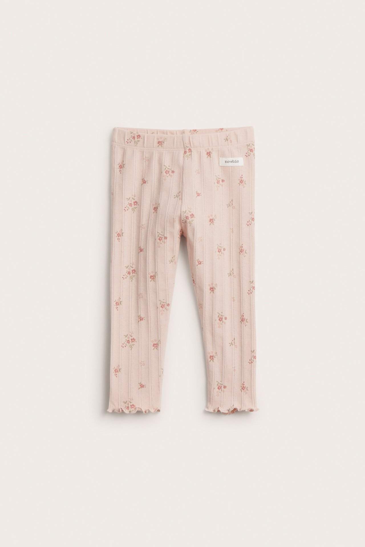 Front view of light pink baby pointelle rib leggings with a floral print and wavy cuffs.