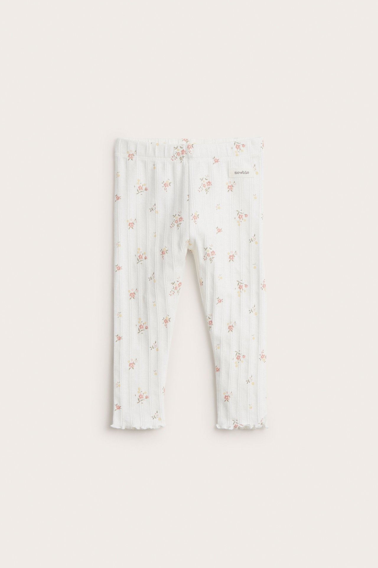 Front view of off-white baby pointelle ribbed leggings with a small floral print and elastic waist.