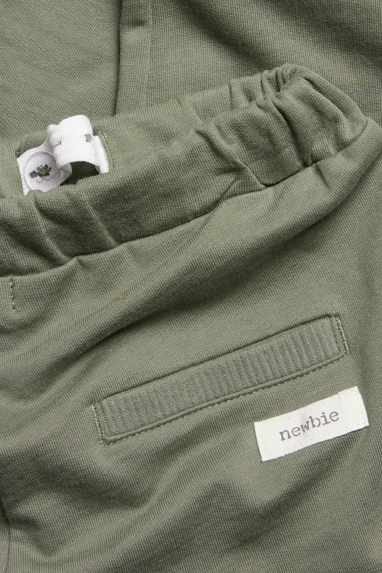 Close-up of dark green kid's cotton jogging pants with adjustable elastic waist and front pocket.