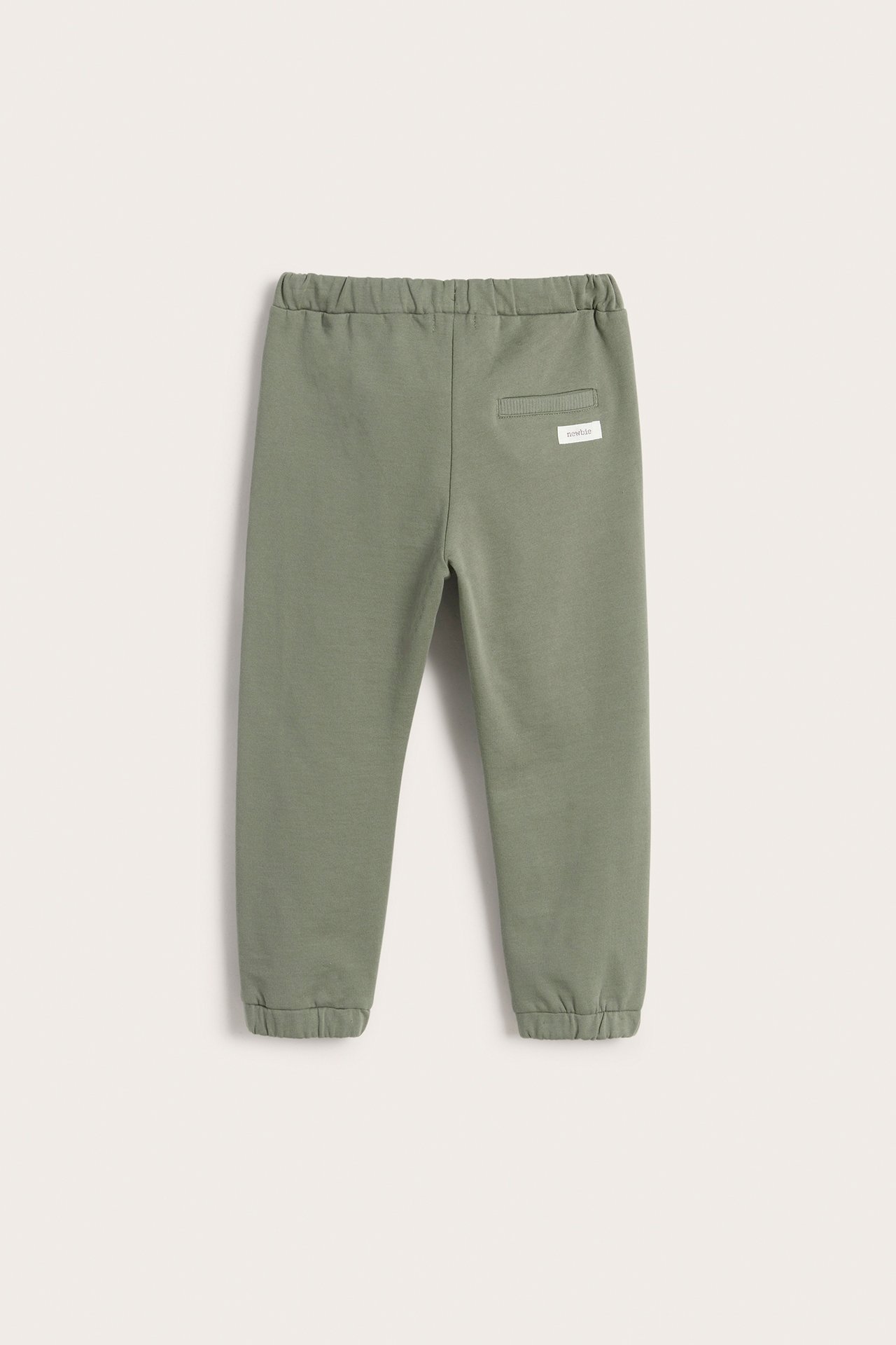 Back view of dark green kid's cotton jogging pants with elasticated waist, cuffs, and a fake back pocket.