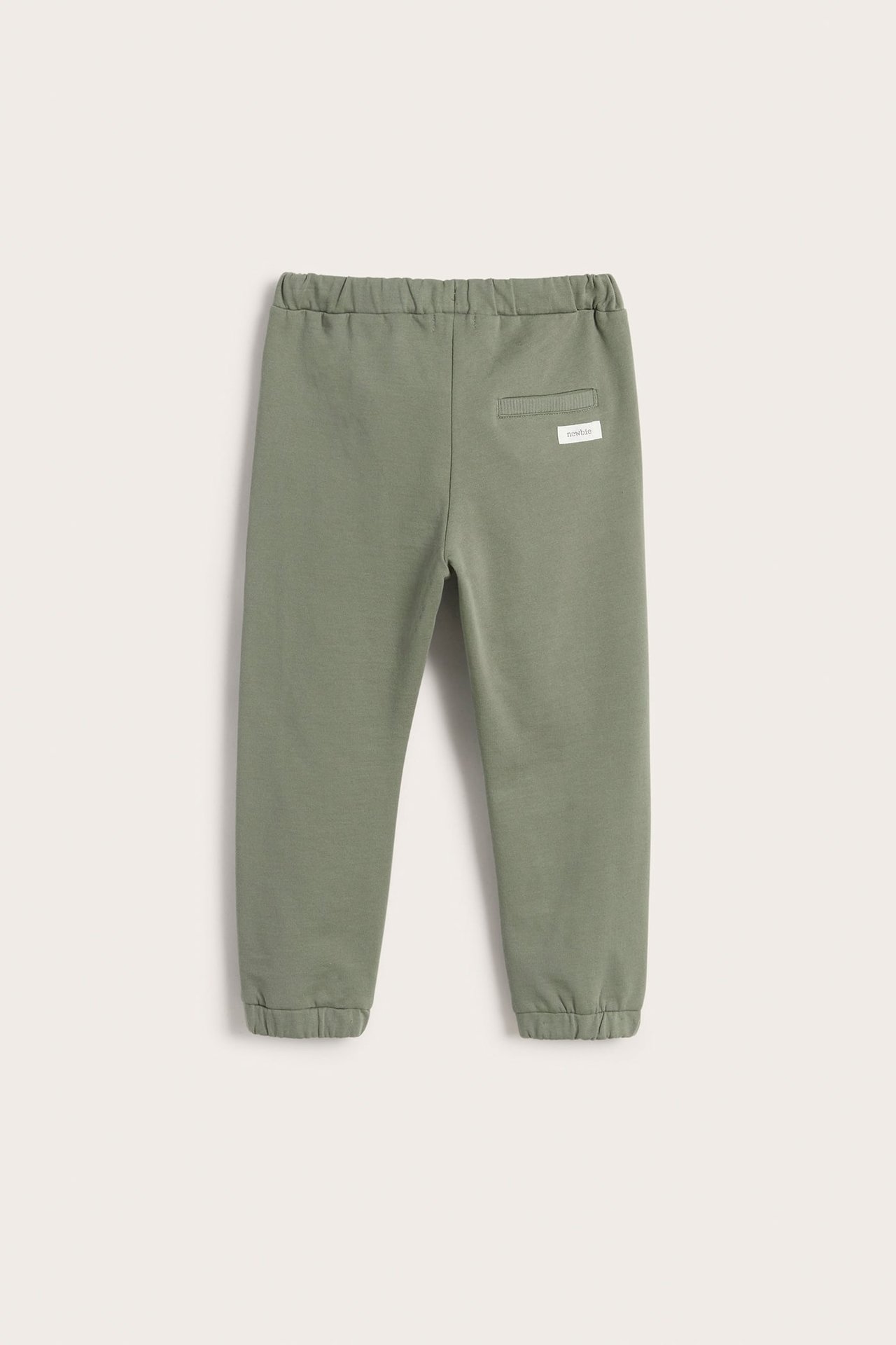 Back view of dark green kid's cotton jogging pants with elasticated waist, cuffs, and a fake back pocket.