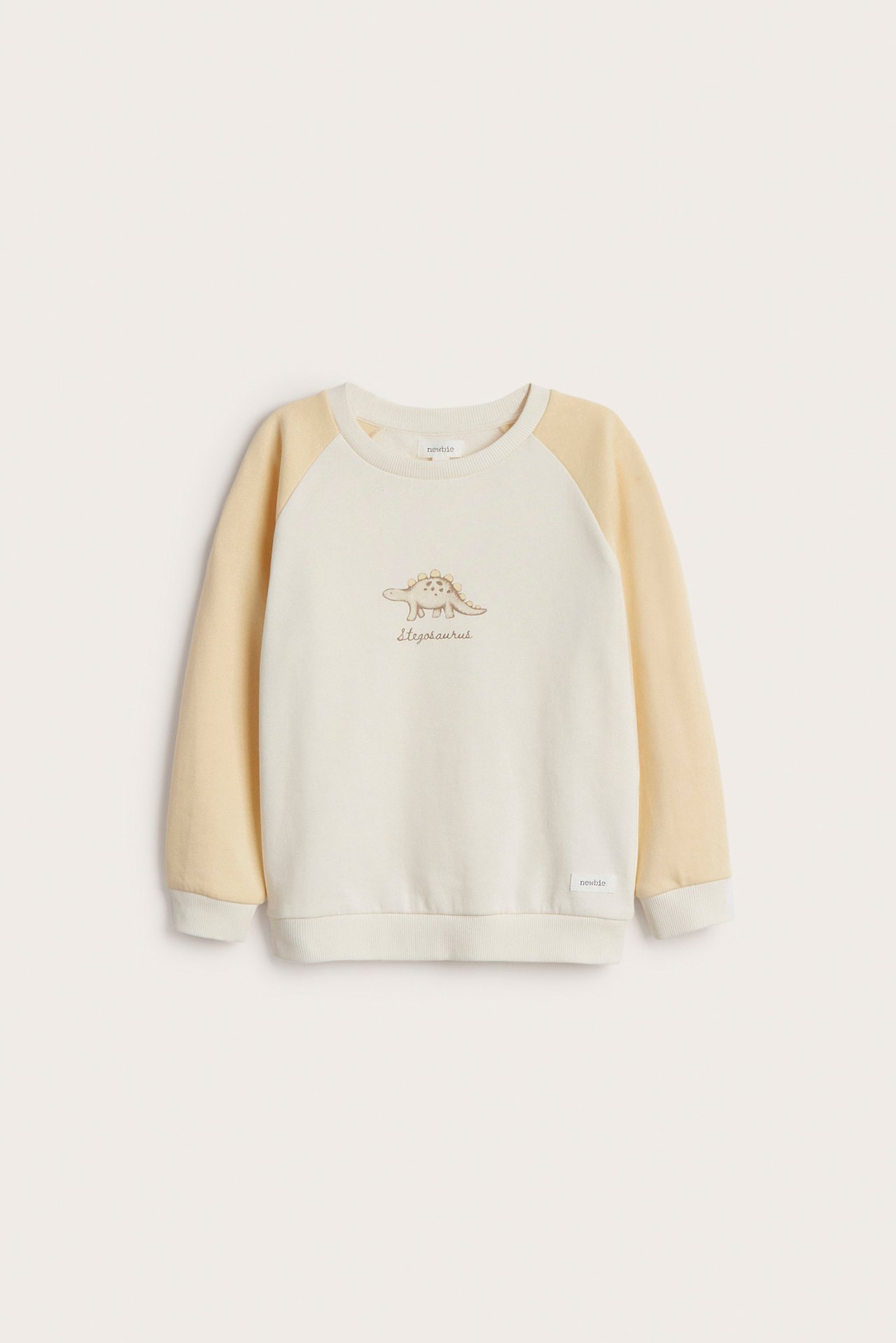 Vorderansicht eines cremefarbenen Kinder-Sweatshirts aus Baumwolle mit hellgelben Raglanärmeln und Stegosaurus-Print.