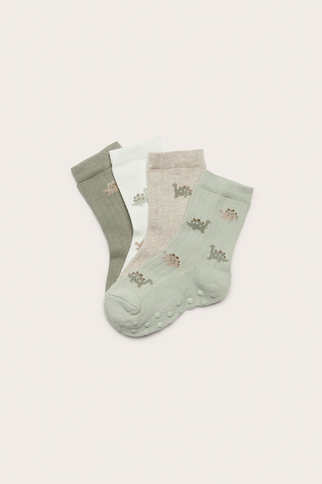 Top-down view: Four ribbed cotton socks in green, off-white, beige, light green with dinosaur patterns. Anti-slip.