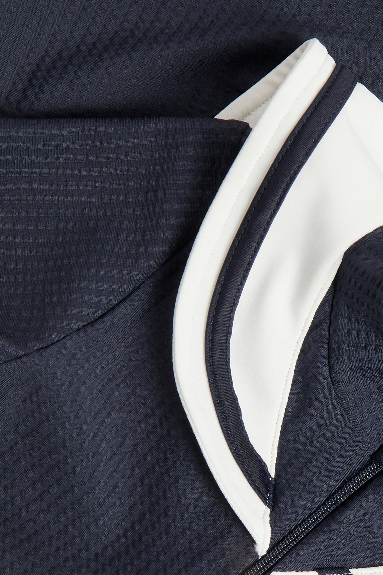 Close-up of a dark blue textured UV suit with a white sailor collar and a front zipper.