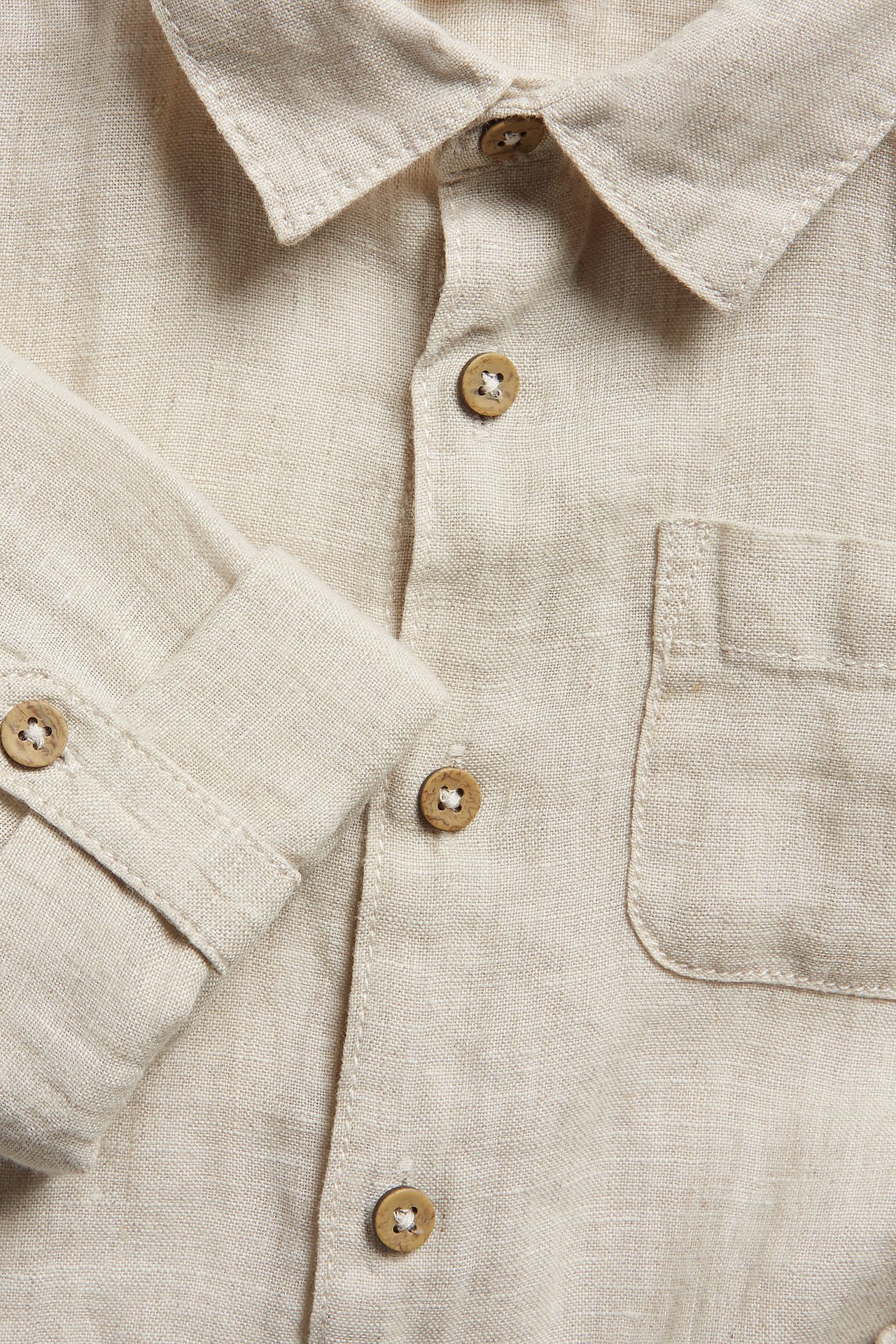 Close-up front view of a light beige linen shirt with rolled sleeves, buttons, and a chest pocket.