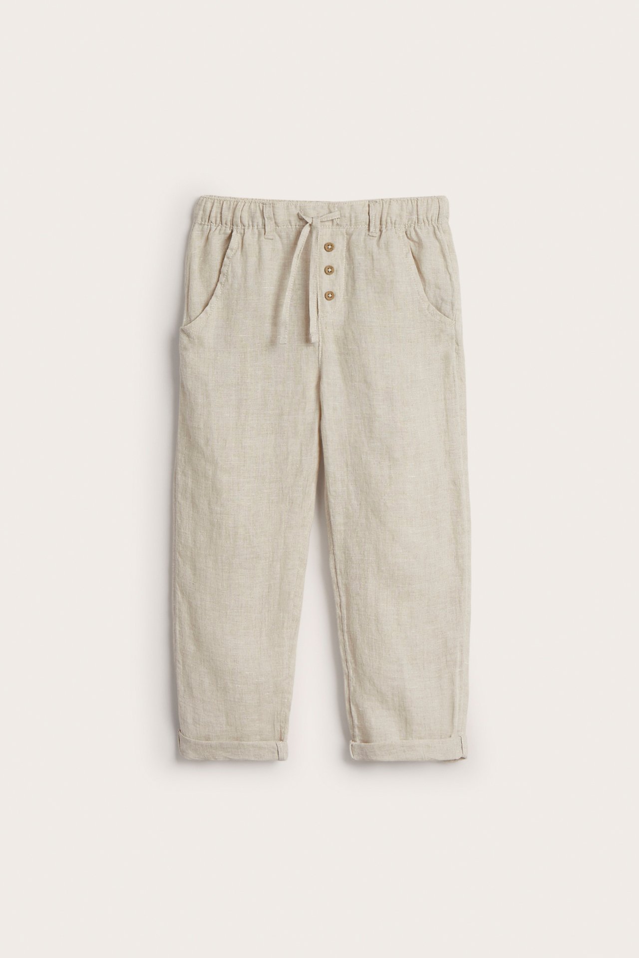 Vorderansicht: Hellbeige Leinenhose mit elastischem Kordelzugbund, Zierknöpfen, Vordertaschen und umgeschlagenen Säumen.