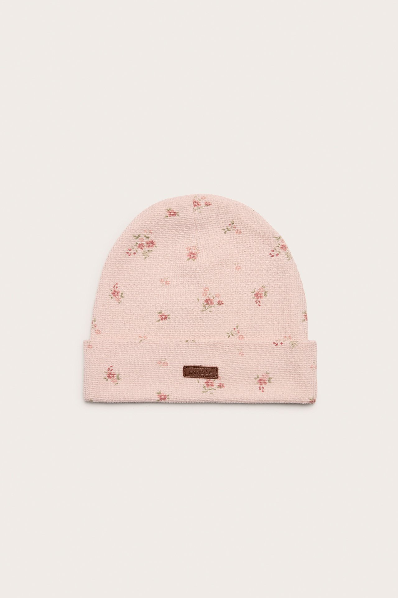 Front view of a light pink jersey beanie with a floral pattern and a fold-up brim.