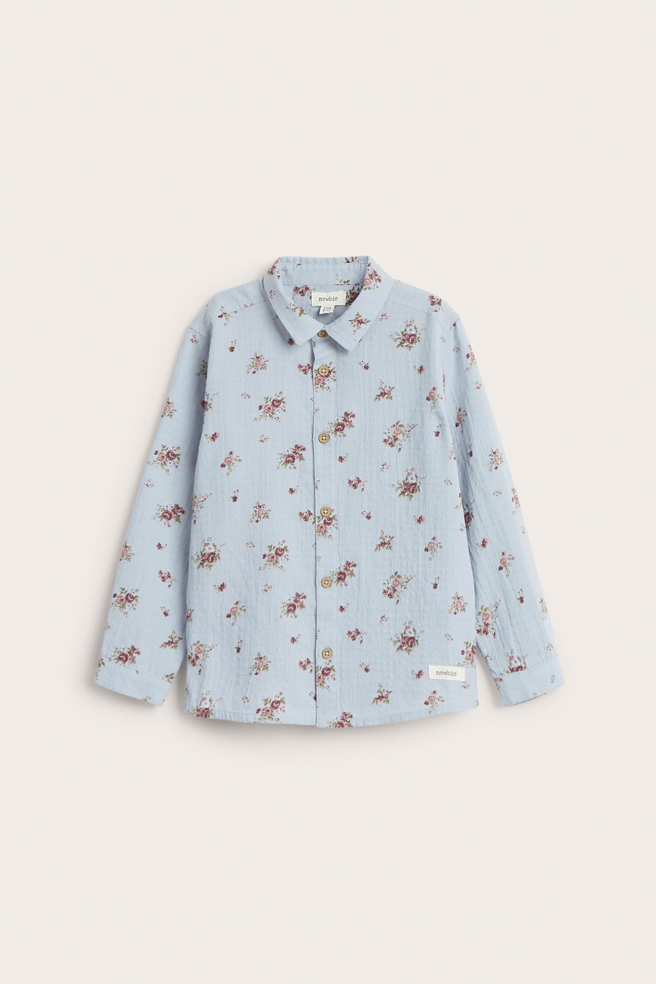 Front view of a kid's light blue cotton shirt with a small floral pattern and brown buttons.