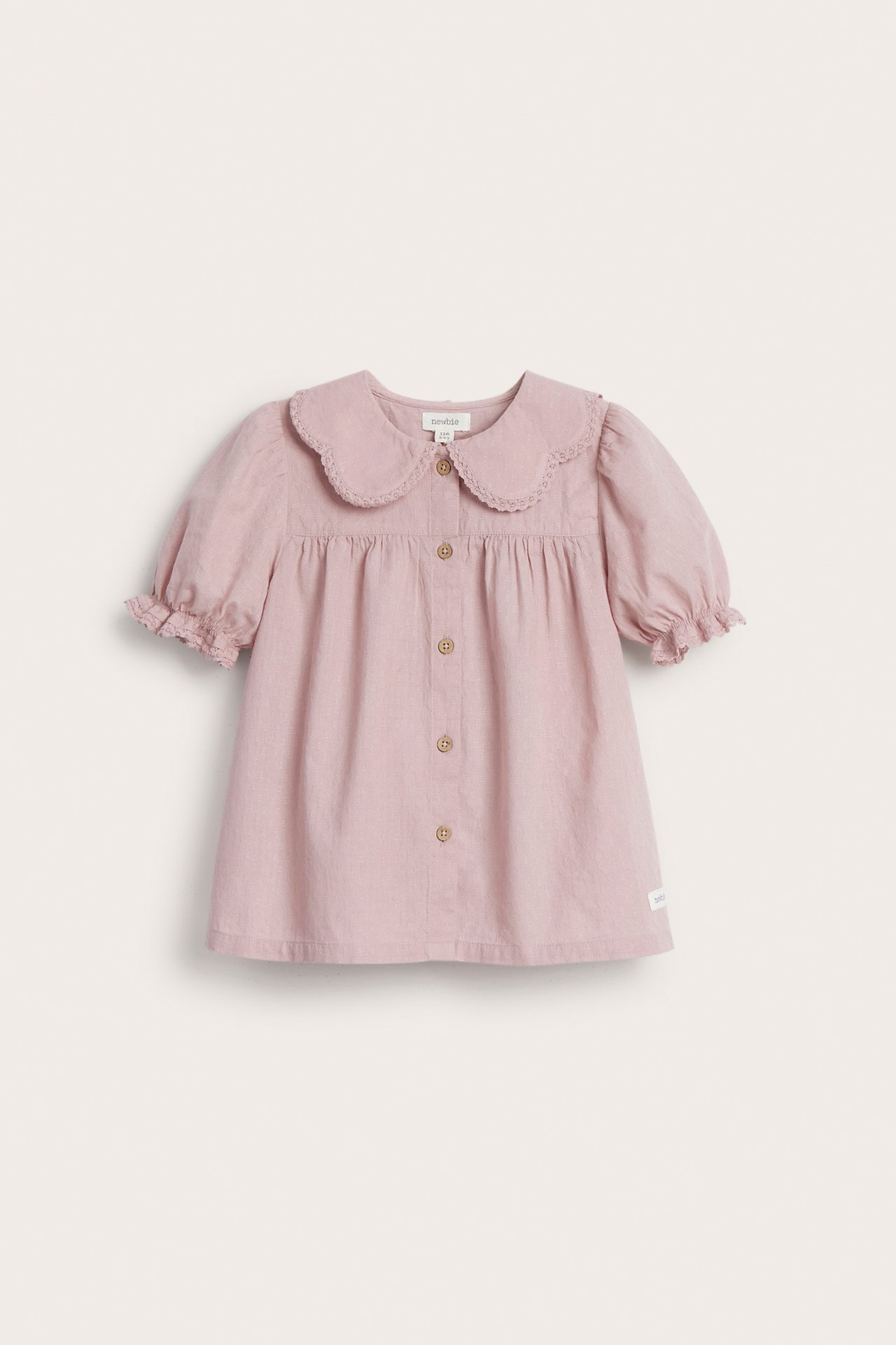 Vorderansicht einer rosa gewebten Kinder-Baumwollbluse mit Spitzenkragen, Puffärmeln und Knöpfen vorne.