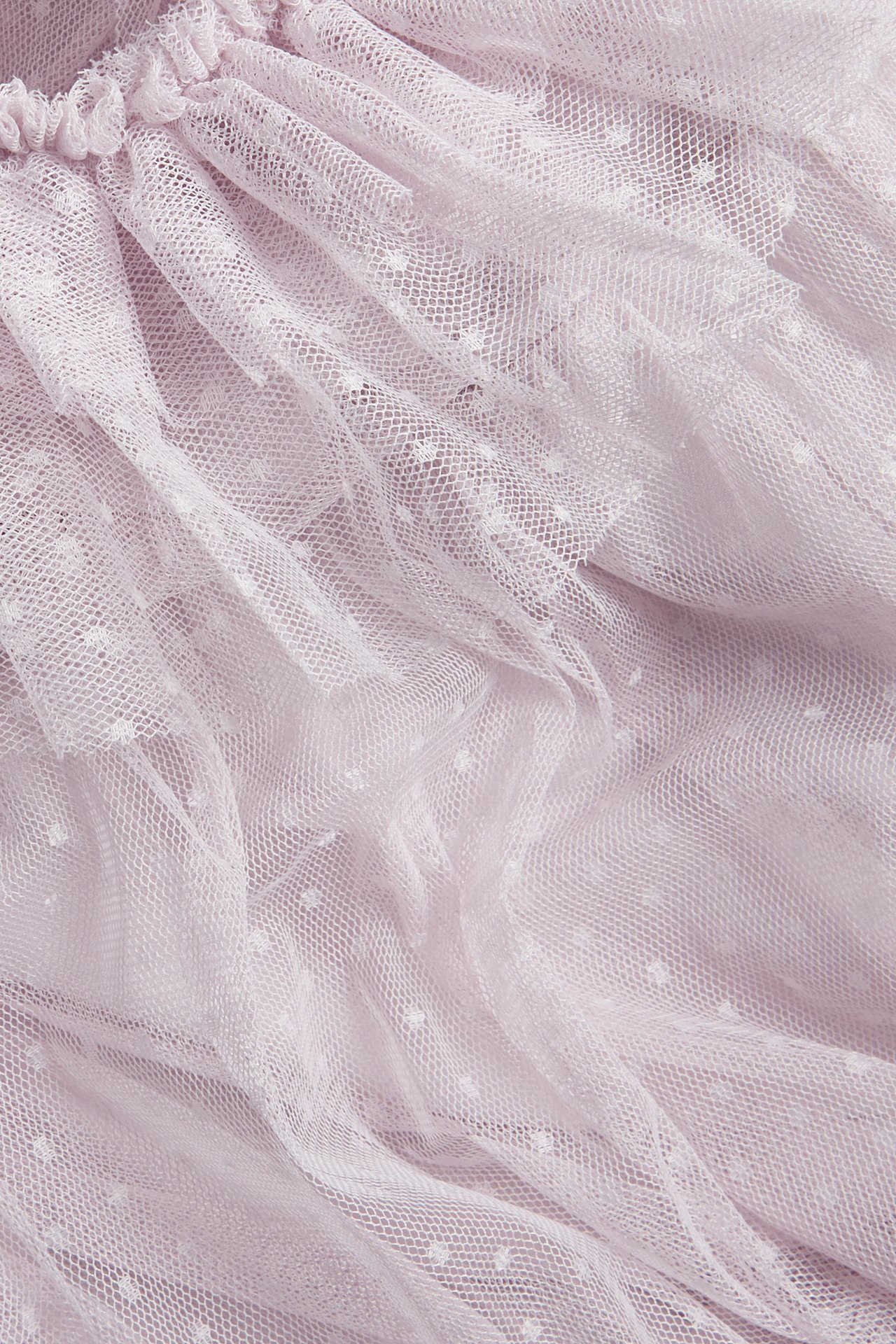 Close-up of light lilac mesh dress fabric with white polka dots and ruffles.