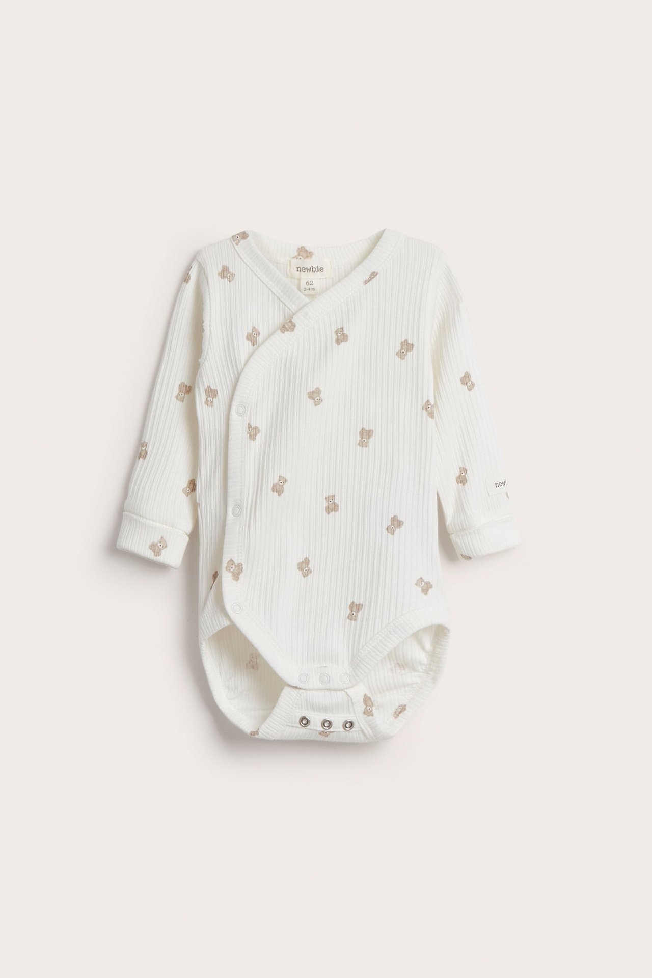 Vorderansicht: Weißer, gerippter Langarm-Babybody mit Teddybärenmuster, Wickeldesign und Druckknöpfen.
