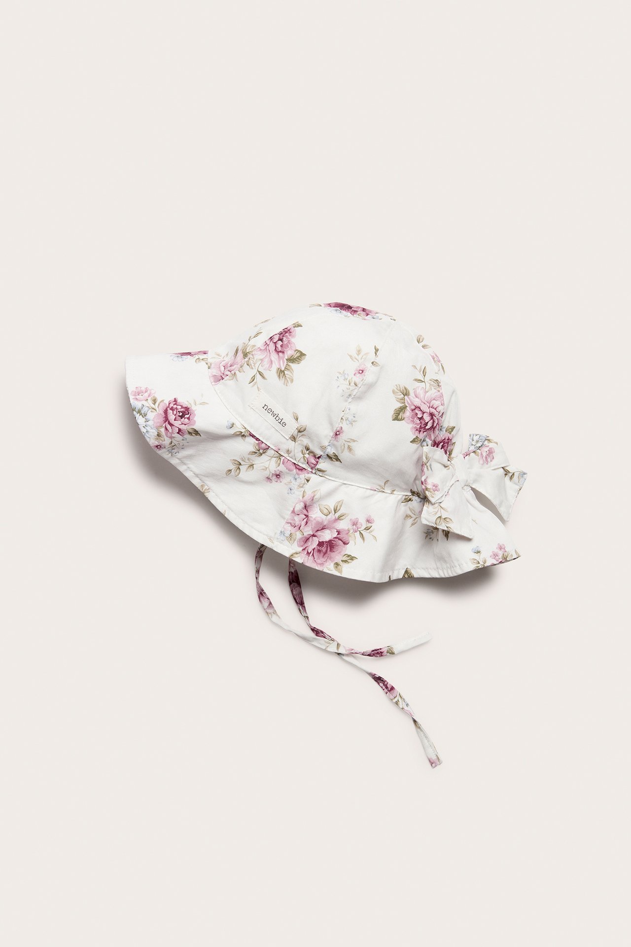 Top view of an off-white floral cotton sun hat for baby/kid with a back bow and tie-bands.