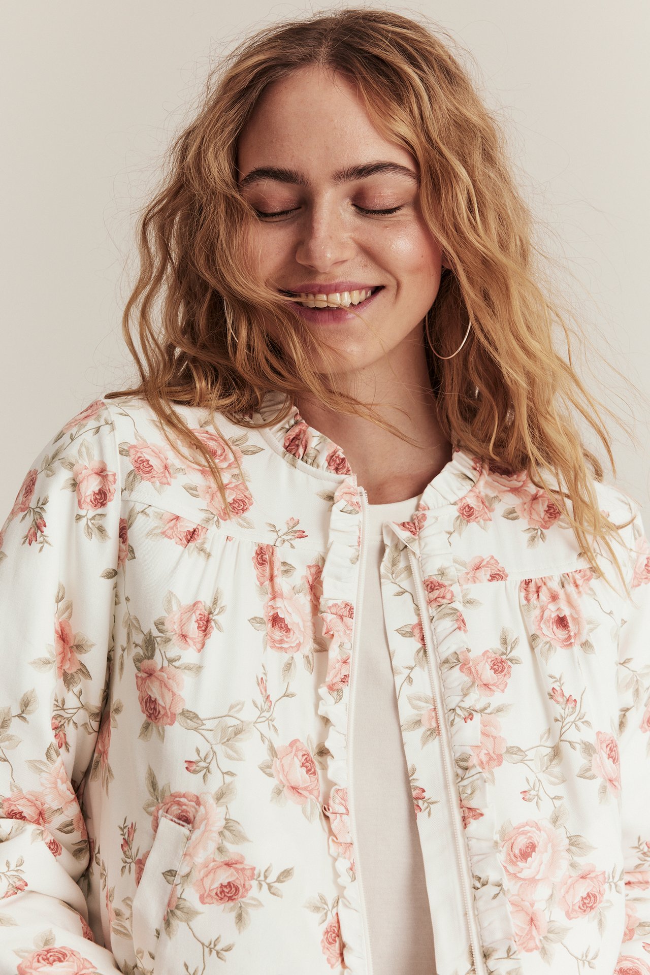 Offwhite floral bomber jacket with ruffle collar, zipper, and two front pockets, woman front view.