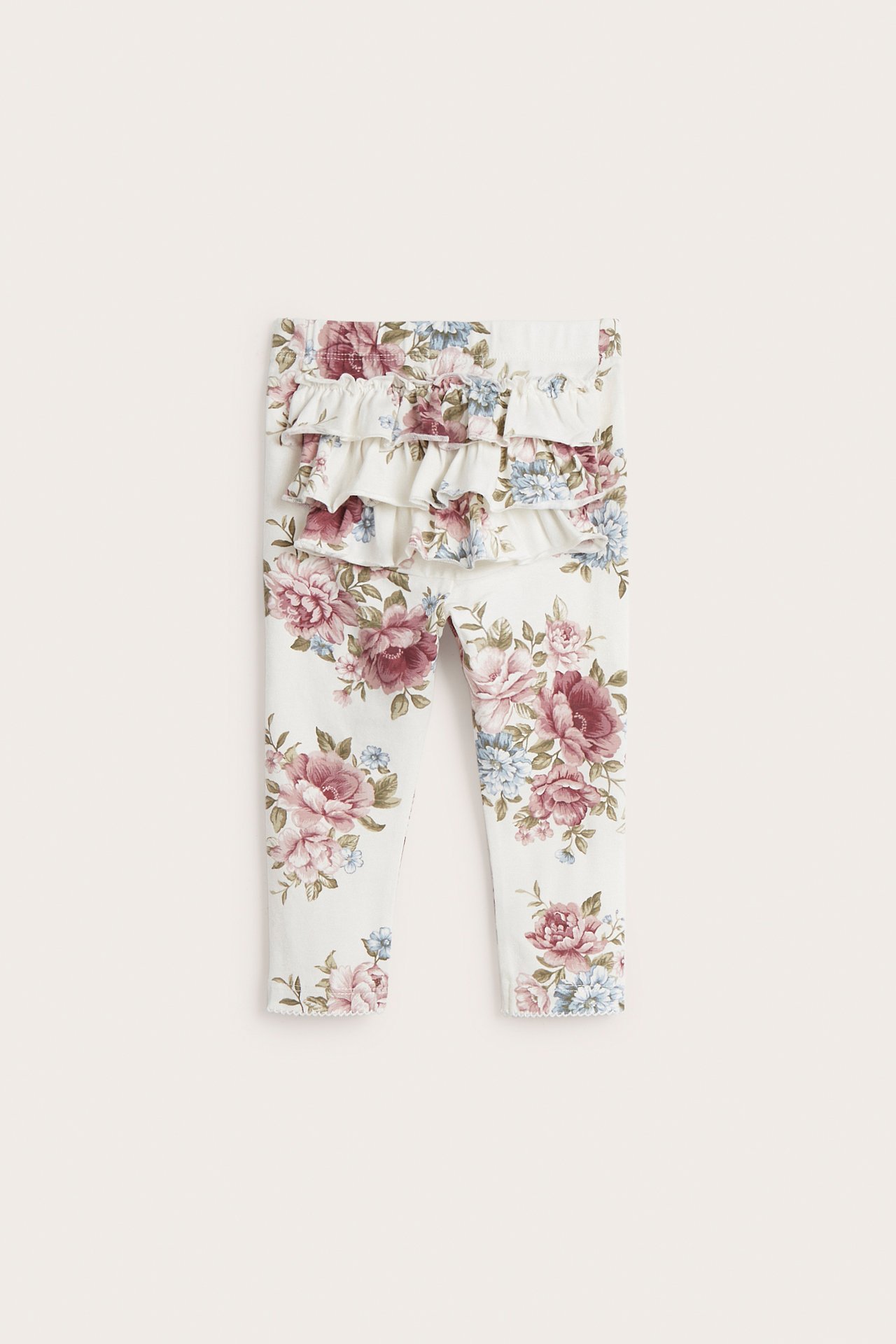 Front view of off-white baby leggings with a floral print and three ruffles at the back.