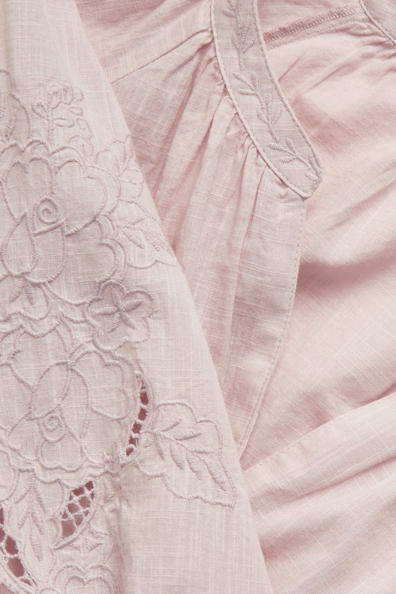 Nahaufnahme einer rosa gewebten Baumwollbluse mit floralen und Blattstickereien.