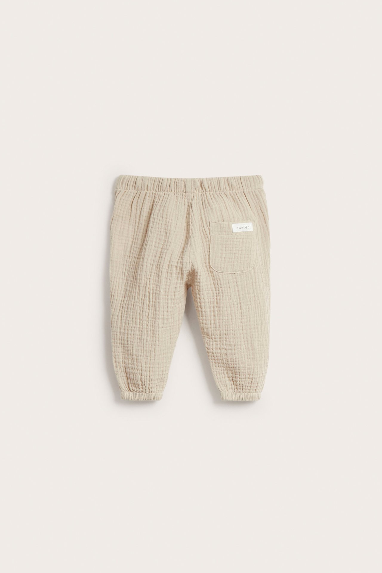 Rückansicht: beige Babyhose aus Baumwollmusselin mit Gummizug in der Taille und Gesäßtasche.