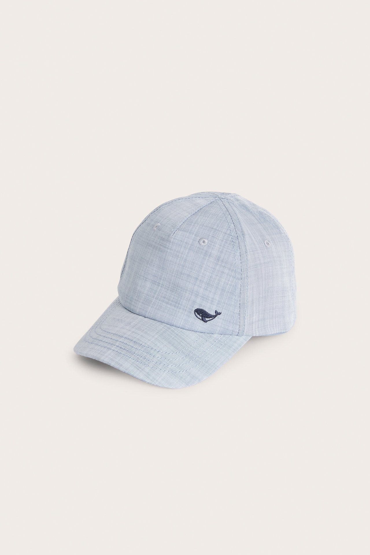 Front-side view of a light blue chambray kid's cap with a small dark blue whale embroidery.