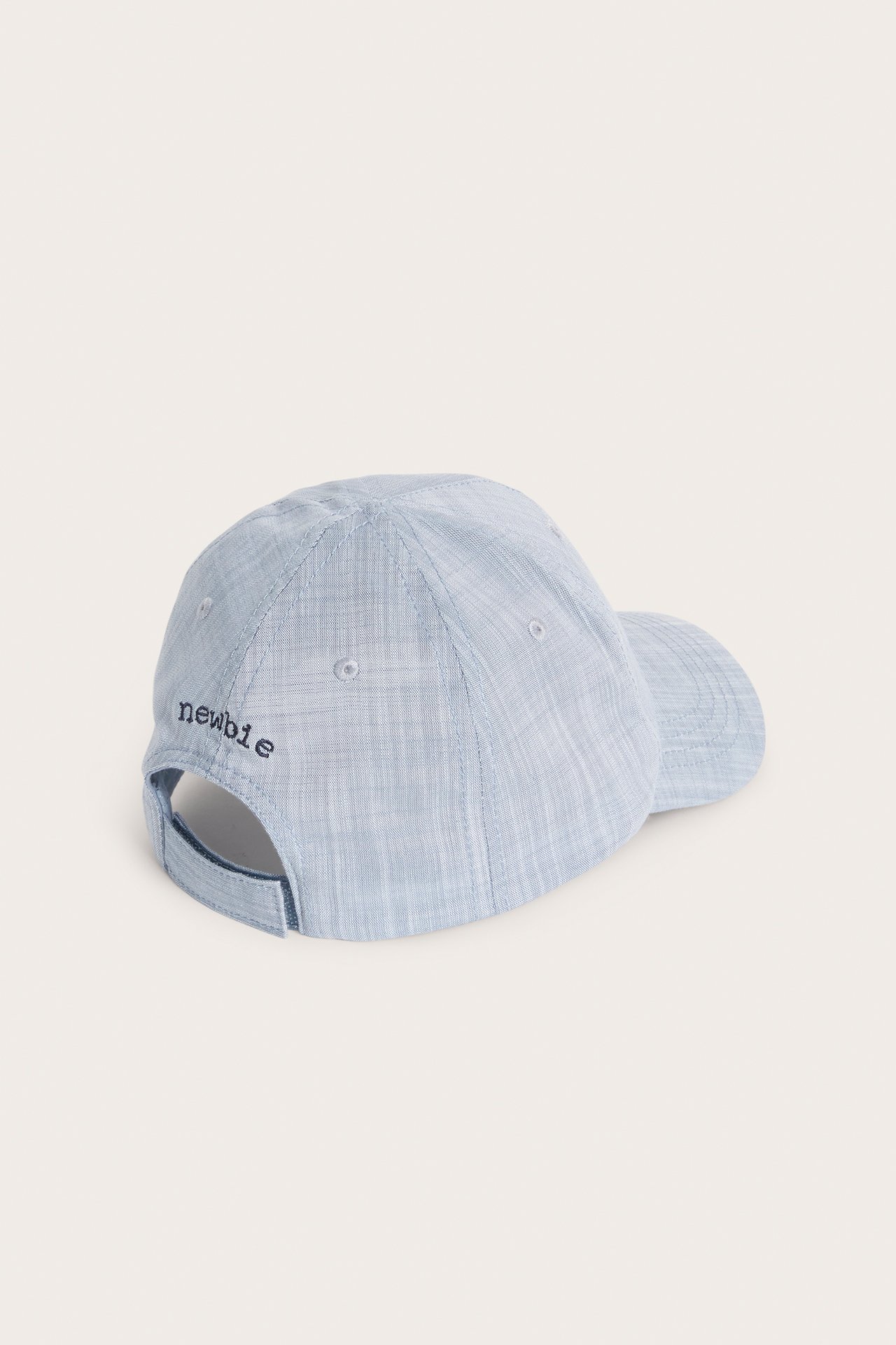 Back-side view of a light blue chambray kid's cap with small embroidery on the back.